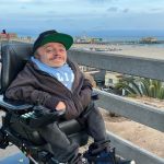 A young white man sits on his wheelchair along the beach in Santa Monica, Cal.